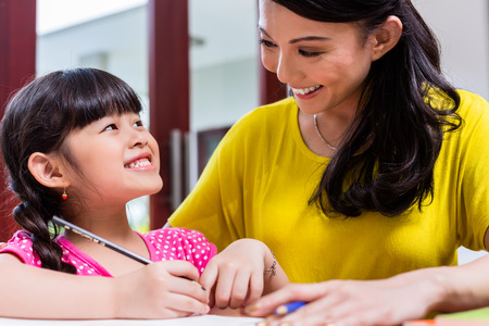 37802110 - chinese mother homeschooling her child teaching her daughter to write