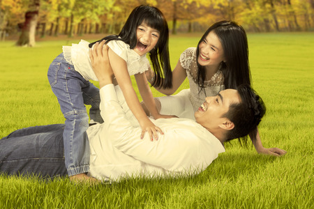 45124962 - portrait of happy asian family enjoying holiday by playing together on the autumn park