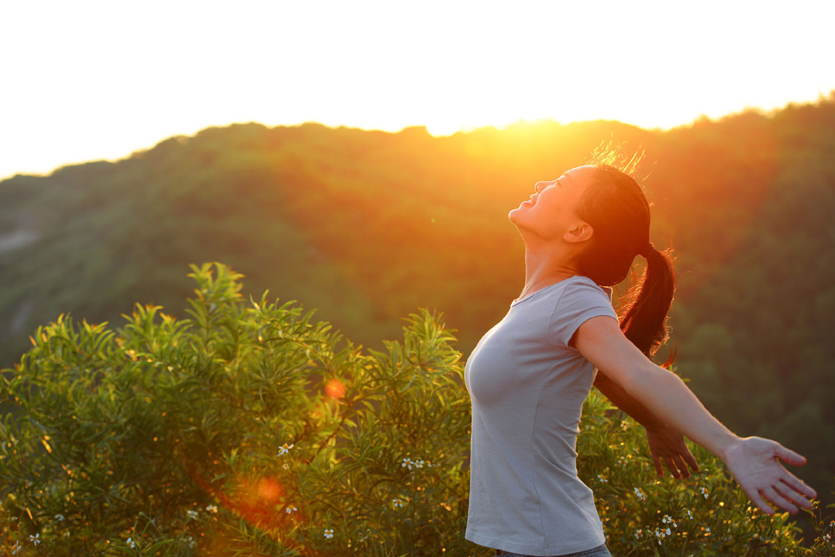 50402902 - cheering woman open arms at sunrise mountain peak