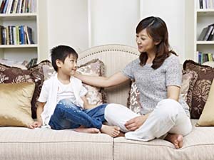 21144465 - asian mother and son having a conversation on couch at home